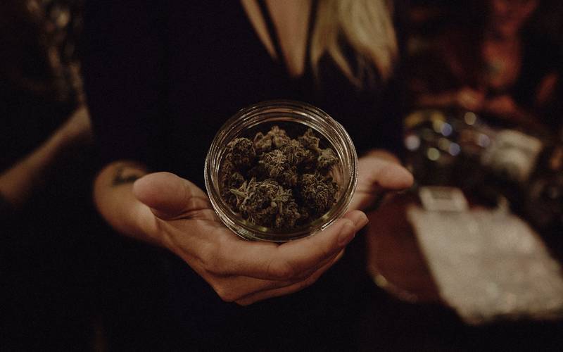 A budtender presenting a jar of craft flower